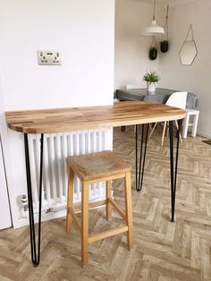 a wooden table with black hairpinks on it and two stools next to it