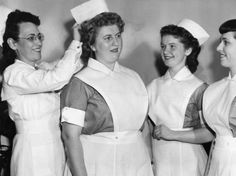 black and white photograph of nurses in uniform smiling at each other with their hats on