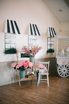 flowers in vases and chairs are on the wooden floor next to an old wagon