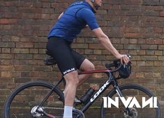 a man is riding his bike in front of a brick wall