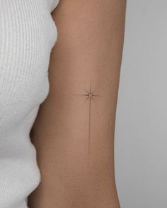 a woman's arm with a small cross tattoo on the back of her left arm