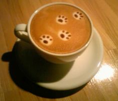 there is a cup of coffee with some animal paw prints on the foam in it