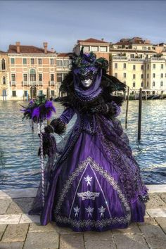 a woman in a purple dress standing next to a body of water