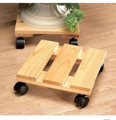 a wooden toy car sitting on top of a hard wood floor next to a potted plant