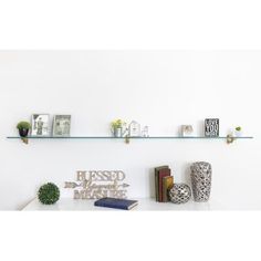 three glass shelves on the wall with books and vases next to each other in front of them