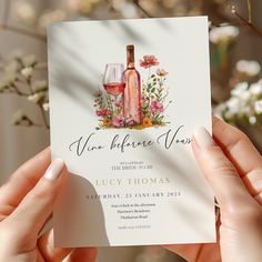 two hands holding up a wine bottle and glass birthday party card with flowers on it