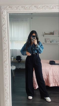 a woman standing in front of a mirror taking a selfie with her cell phone