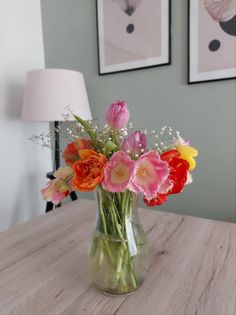 a vase filled with flowers sitting on top of a wooden table next to a lamp