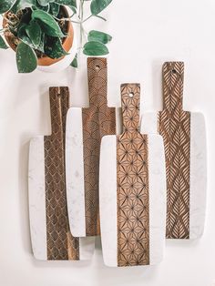 five decorative wooden pieces sitting on top of a white table next to a potted plant