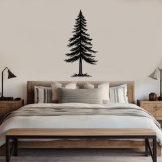 a bed room with a neatly made bed and a wall decal that has a pine tree on it