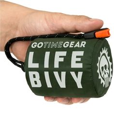 a hand holding a green bag with the words go time gear life bivy printed on it