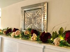 a mantel decorated with flowers and greenery