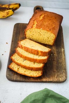 sliced loaf of banana bread sitting on top of a cutting board next to some bananas