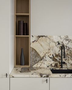 a kitchen with white cabinets and marble counter tops, black faucet sink and wooden shelves