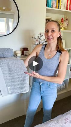 a woman standing in front of a bed holding something