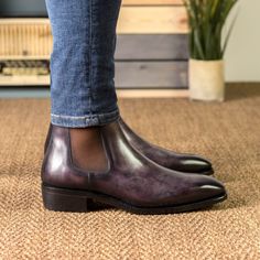 a person standing on top of a carpet next to a potted plant and wearing brown shoes