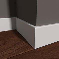 the corner of a room with wood flooring and white trim on the walls is shown