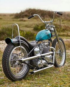 a blue motorcycle parked on top of a grass covered field