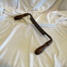 an old wooden handle laying on top of a white bed sheet covered in sheets and pillows