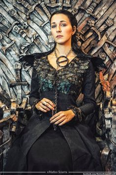 a woman sitting on top of a iron throne with chains around her neck and hands