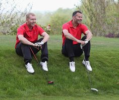 two men sitting on the grass playing golf