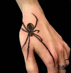 a hand with a black spider tattoo on it