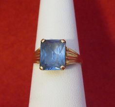 An Original 1960's Swedish 18 Kt Yellow Gold Blue Topaz Ladies Ring - Blue Beauty (Size 6). Visit this shop for a wide variety of Vintage Quality Jewelry, Art, and Collectibles.~Age (approximate): 1960's~Material(s): 18 Karat Yellow Gold~Approx. Size: 6~Approx. Weight: 1.4 dwt~Signature / Brand: Unsigned. ~Condition: Very Good. ~International Shipping: Is Available, please contact us for a quote.~Inventory #: 6129 Classic Blue Topaz Solitaire Ring, Formal Blue Solitaire Topaz Ring, Formal Blue Topaz Solitaire Ring, Blue Topaz Solitaire Ring For Formal Occasions, Emerald Cut Blue Sapphire Ring With 17 Jewels, Classic Blue Emerald-cut Topaz Ring, Vintage Blue Emerald Cut Jewelry, Blue Vintage Jewelry With Center Stone, Antique Blue Sapphire Ring Collectible