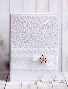 a close up of a card on a wooden table with white paper and pink flowers