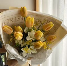 a bouquet of yellow and white flowers sitting on top of a table