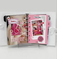 an open planner book with pink hair and white ribbon around the pages is on display