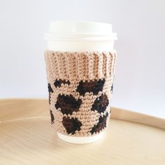 a knitted coffee cup cozying on top of a wooden tray