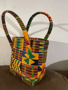 "This bag is made with kente cloth material.  Dimensions: 16\" W X 11\" H X 7\" D" Multicolor Fabric Bag With Handles, Fabric Multicolor Bag, Multicolor Fabric Bag With Double Handle, Multicolor Fabric Shoulder Bag With Double Handle, Yellow Fabric Rectangular Bag, Multicolor Double Handle Fabric Shoulder Bag, Yellow Rectangular Fabric Bag, Multicolor Fabric Shoulder Bag For Shopping, Multicolor Bucket Satchel With Top Carry Handle