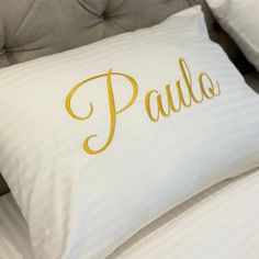 a pillow with the word paul on it sitting on top of a bed next to pillows