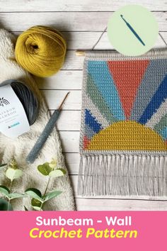 the sunbeam wall hanging is next to some yarn and needles on a white wooden surface