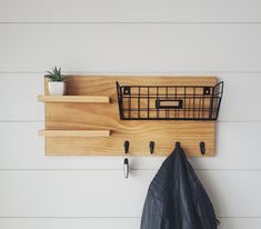 the coat rack is made from wood and has two hooks on it, along with a leather jacket hanger