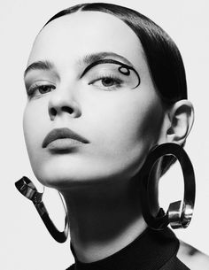 a black and white photo of a woman with large hoop earrings on her head, looking to the side