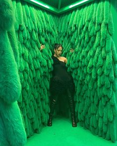 a woman is standing in the middle of a room made out of fake green trees