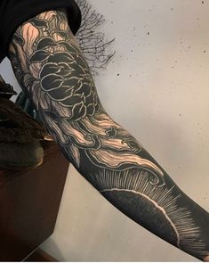 a man's arm covered in black and grey ink with an intricate design on it