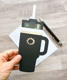 a person holding up a card with a coffee cup on it