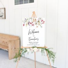 a welcome sign sitting on top of a easel in front of a white building