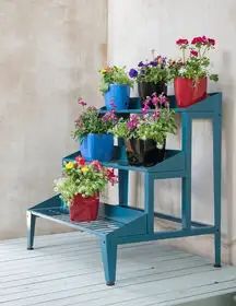 three blue plant stands with flower pots on them and one shelf holding flowers in it