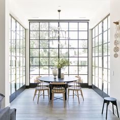 a dining room table and chairs in front of large windows