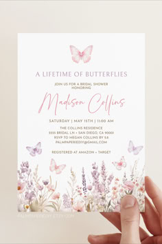 a person holding up a card with flowers and butterflies on it, in front of a white background