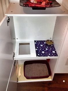 a cat litter box in the corner of a cabinet with food and water on it