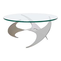 a glass and metal coffee table with an abstract design on the top, against a white background