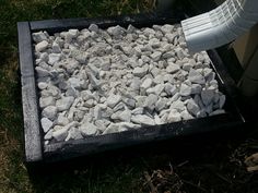 a pile of white rocks sitting on top of a grass covered ground next to a trash can