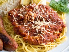 spaghetti, sausage and bread on a white plate