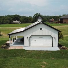 a white garage in the middle of a green field