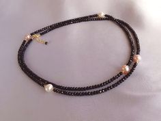 This elegant long necklace was set up using  faceted black spinel rondelles, ivory and salmon pink cultured pearls and yellow gold filled findings. Available also in silver or rose gold finish.  Necklace length is 80 cm ~ 31.5 inches plus an adjustable extension chain of 2.5 cm ~ 1 inch.  Materials: ~ 3 mm black spinel faceted rondelles ~ cultured pearls ~ gold filled/sterling silver findings Black Spinel is a protective stone that repels negativity and grounds the user.  Use Black Spinel to get rid of anger and resentment, replacing them with more effective ways of communicating.  Black Spinel gives one inspiration and a better sense of empowerment, without overwhelming others. Physically, use Black Spinel for detoxifying the body.  It can heal the body as a whole, but is often helpful fo Luxury Black Diamond And Black Spinel Necklace, Elegant Black Rondelle Beaded Necklaces, Black Gemstone Necklace, Black Spinel Necklace, Spinel Necklace, Black Pearl Necklace, Black Spinel, Necklace Long, Salmon Pink