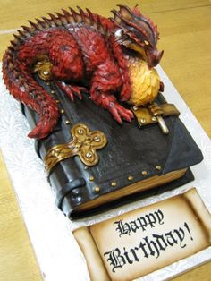 a birthday cake made to look like a book with a dragon on it's cover